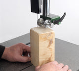 Person using a band saw fit with the Crobra Scroll Guide system to cut a wooden block on a white background